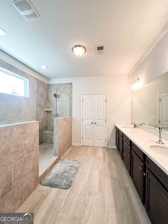 bathroom featuring tiled shower and vanity