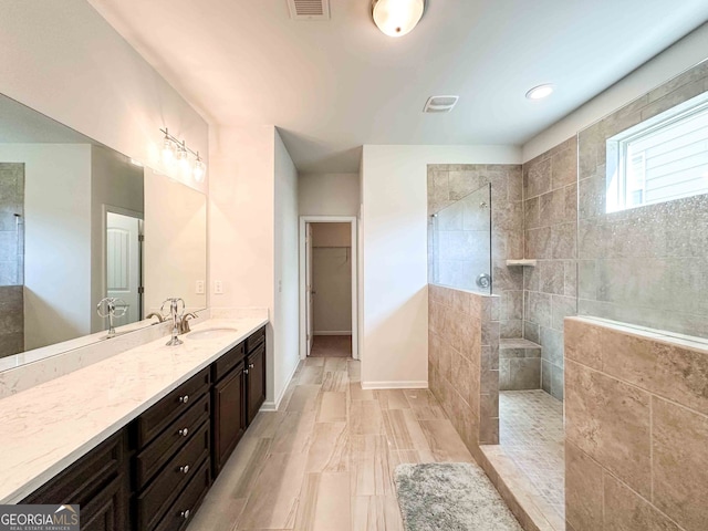 bathroom with tiled shower and vanity