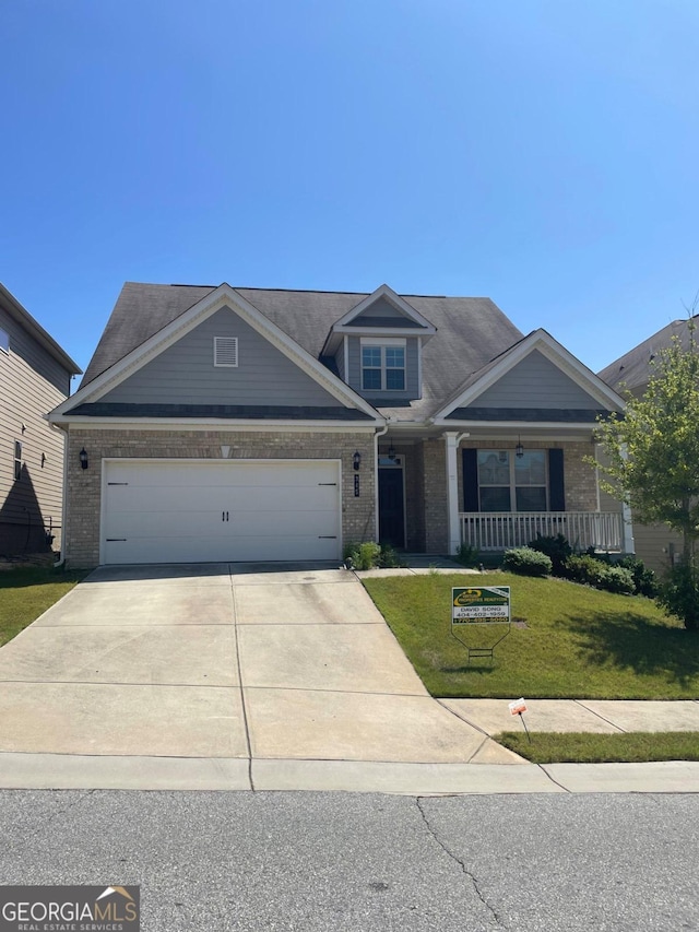 view of front of property with a garage, covered porch, and a front yard