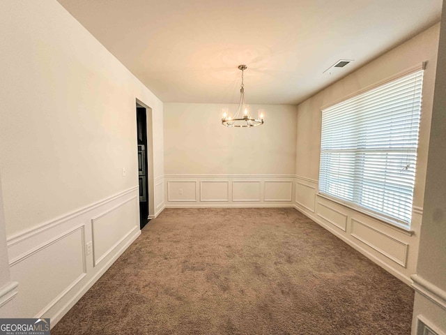 carpeted empty room featuring an inviting chandelier