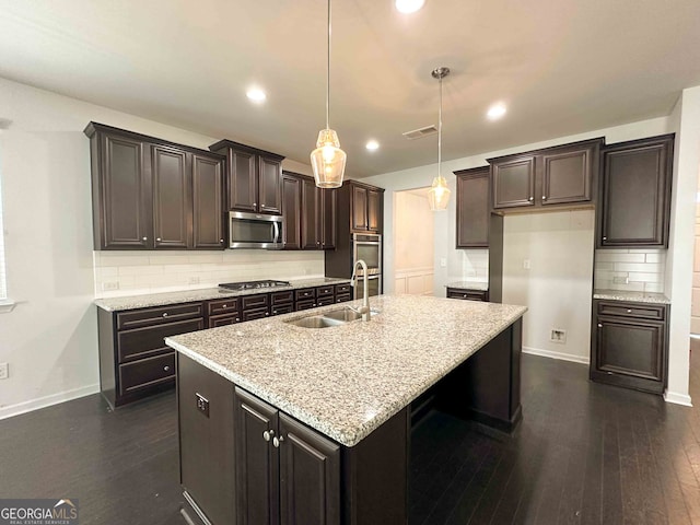 kitchen with a kitchen island with sink, appliances with stainless steel finishes, decorative light fixtures, and sink