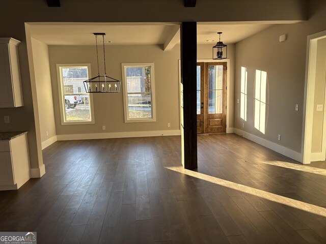 unfurnished dining area with beam ceiling, an inviting chandelier, and dark wood-type flooring