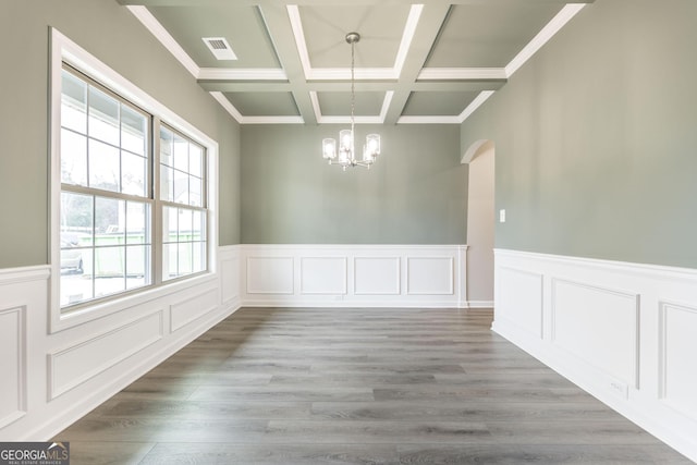 unfurnished dining area with an inviting chandelier, hardwood / wood-style floors, coffered ceiling, and beamed ceiling