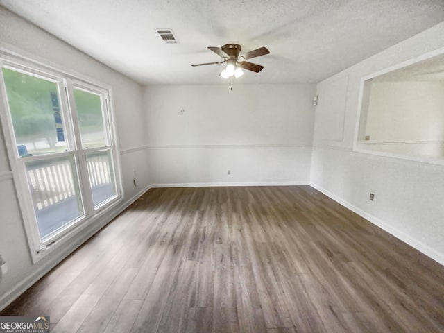 unfurnished room with baseboards, visible vents, ceiling fan, wood finished floors, and a textured ceiling