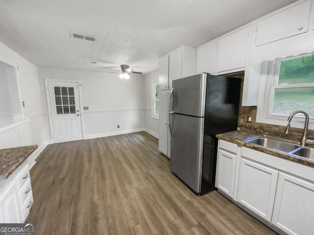 kitchen featuring freestanding refrigerator, white cabinets, a sink, and wood finished floors