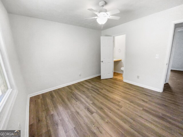 unfurnished bedroom with a ceiling fan, baseboards, wood finished floors, and ensuite bathroom