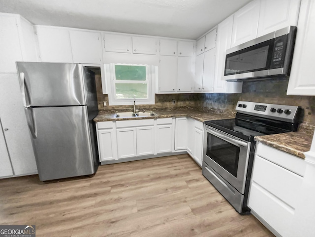 kitchen featuring a sink, light wood-style floors, white cabinets, appliances with stainless steel finishes, and tasteful backsplash