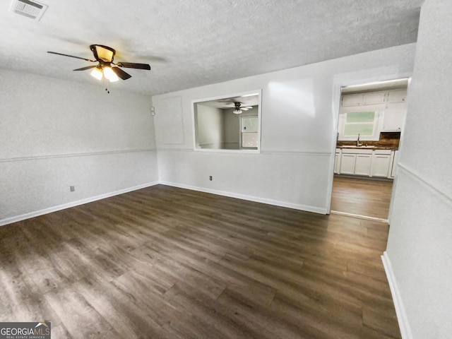 spare room with visible vents, dark wood-type flooring, a sink, a textured ceiling, and baseboards