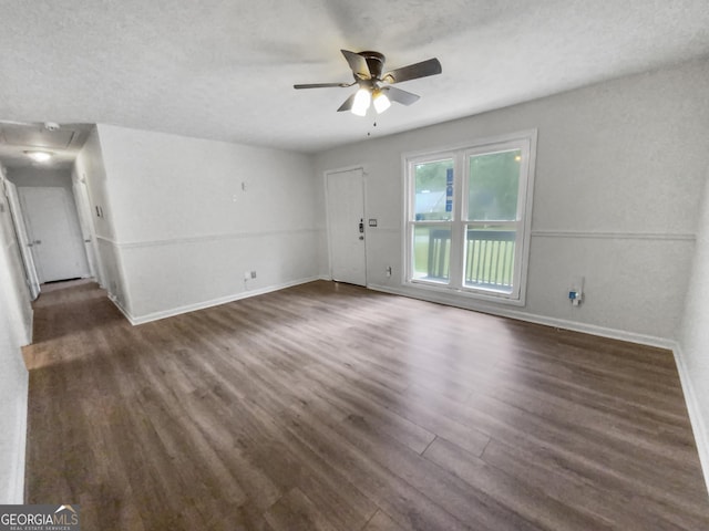 unfurnished living room featuring a ceiling fan, a textured ceiling, baseboards, and dark wood-type flooring