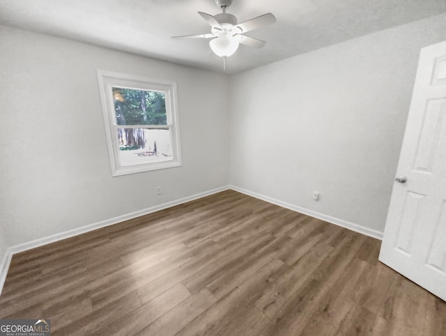 unfurnished room with ceiling fan, dark wood-type flooring, and baseboards