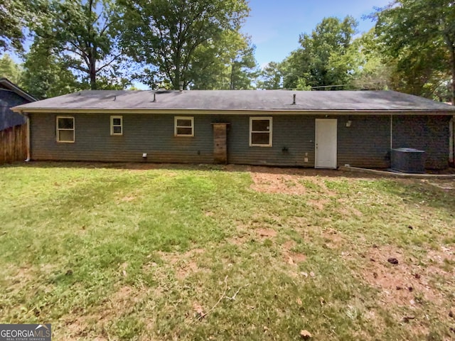 rear view of property featuring central air condition unit and a lawn