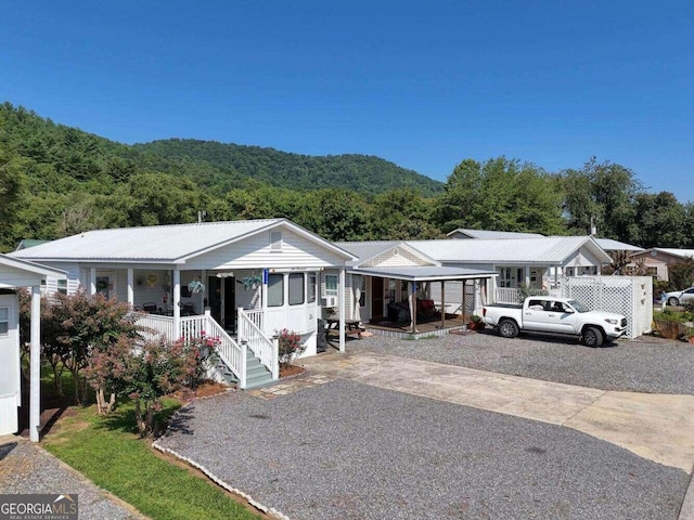 ranch-style house with covered porch, driveway, and a view of trees