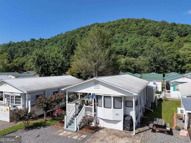 manufactured / mobile home featuring covered porch, metal roof, and a view of trees