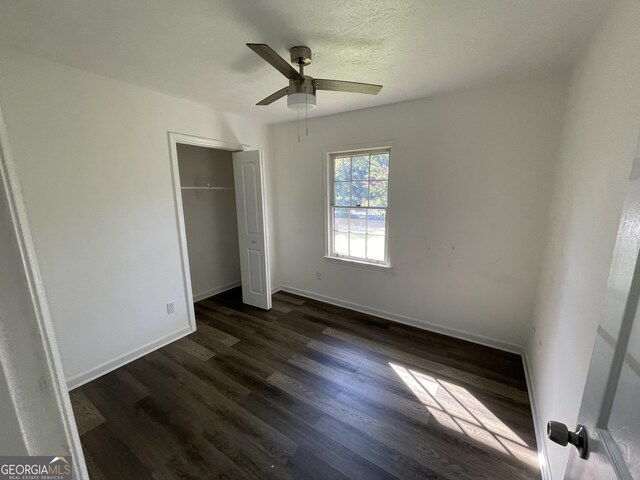 unfurnished bedroom featuring ceiling fan, a closet, and dark hardwood / wood-style flooring