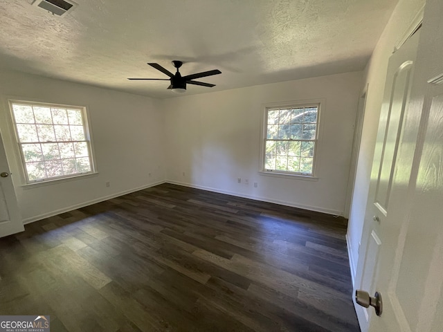 unfurnished room with ceiling fan, plenty of natural light, a textured ceiling, and dark wood-type flooring