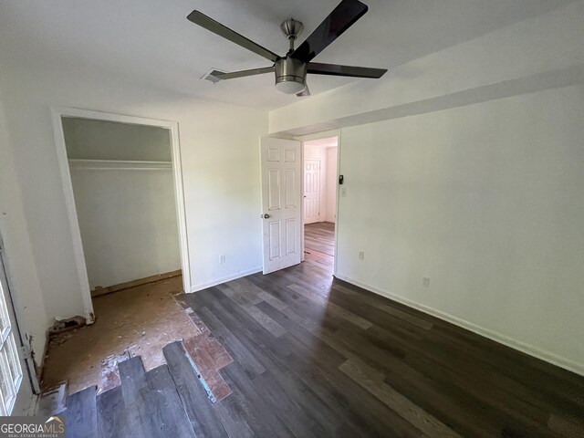 unfurnished bedroom featuring ceiling fan, a closet, and dark wood-type flooring