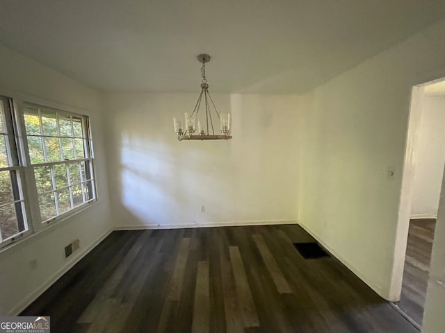 unfurnished dining area featuring dark wood-type flooring and a chandelier