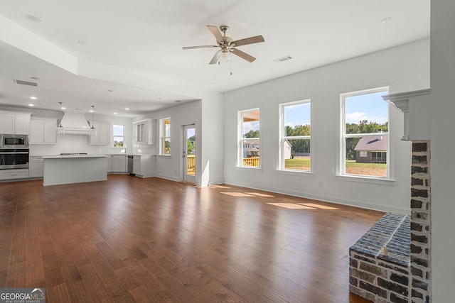 unfurnished living room with baseboards, visible vents, and dark wood finished floors