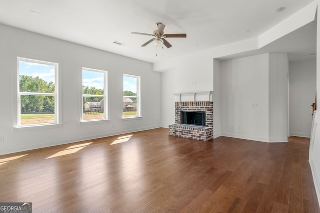 unfurnished living room featuring dark wood-type flooring, a brick fireplace, visible vents, and baseboards