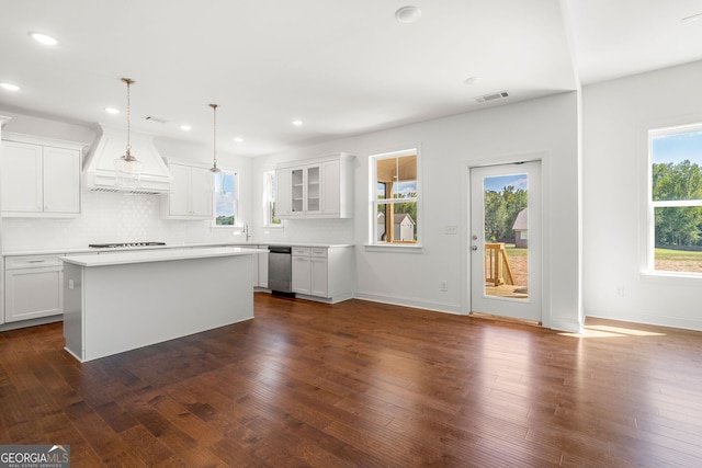 kitchen featuring pendant lighting, light countertops, glass insert cabinets, white cabinets, and a kitchen island