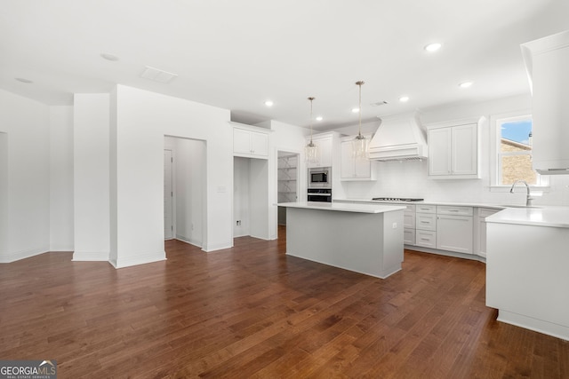 kitchen featuring white cabinets, a kitchen island, custom exhaust hood, stainless steel appliances, and light countertops