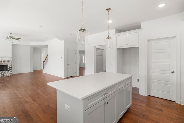 kitchen with ceiling fan, a kitchen island, open floor plan, light countertops, and pendant lighting