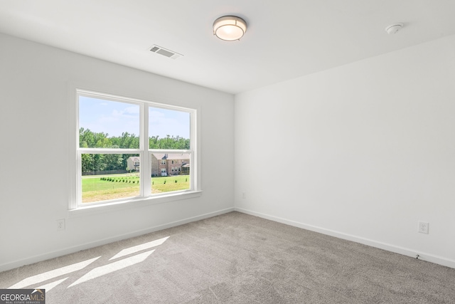 spare room with carpet floors, visible vents, and baseboards