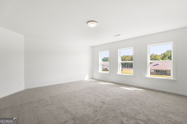 empty room with carpet, visible vents, and baseboards