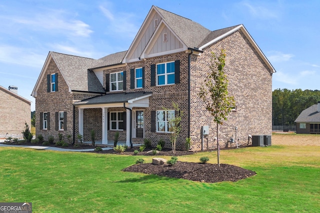 view of front of house with central air condition unit, a shingled roof, brick siding, a front lawn, and board and batten siding