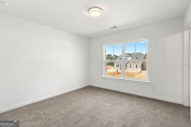 empty room with baseboards, visible vents, and carpet flooring