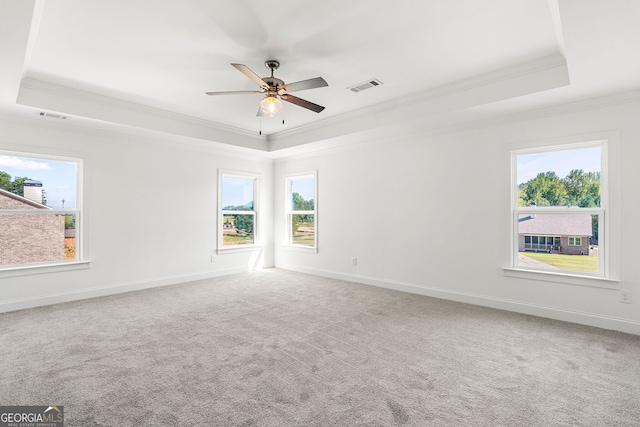 spare room with a tray ceiling, crown molding, visible vents, carpet flooring, and baseboards