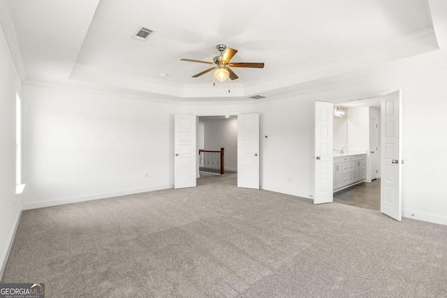 unfurnished bedroom with crown molding, a raised ceiling, light colored carpet, visible vents, and baseboards