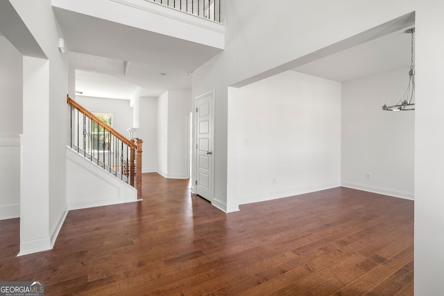 empty room with stairs, baseboards, and dark wood-type flooring