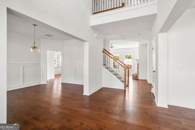 entryway with stairs, dark wood-style flooring, visible vents, and a decorative wall