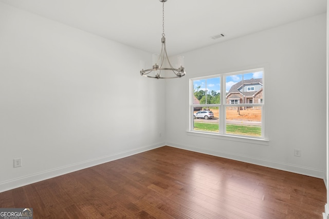 unfurnished dining area featuring baseboards, wood finished floors, visible vents, and an inviting chandelier