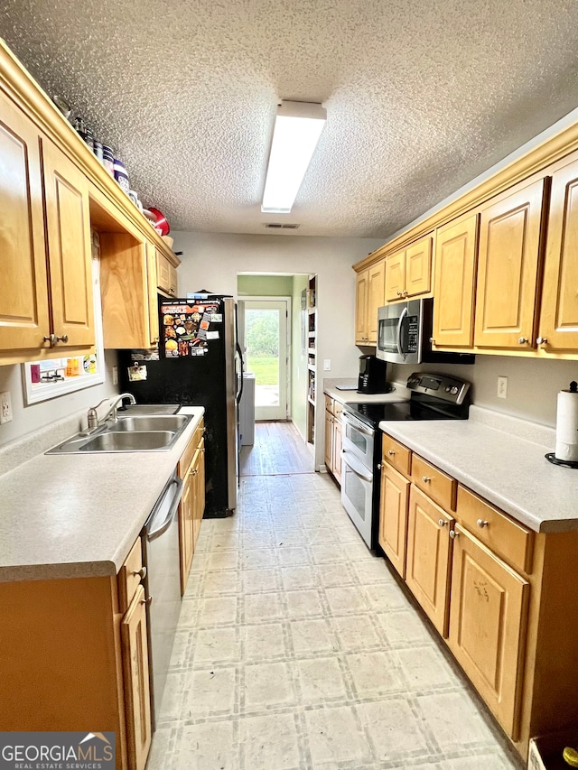 kitchen with a textured ceiling, appliances with stainless steel finishes, and sink