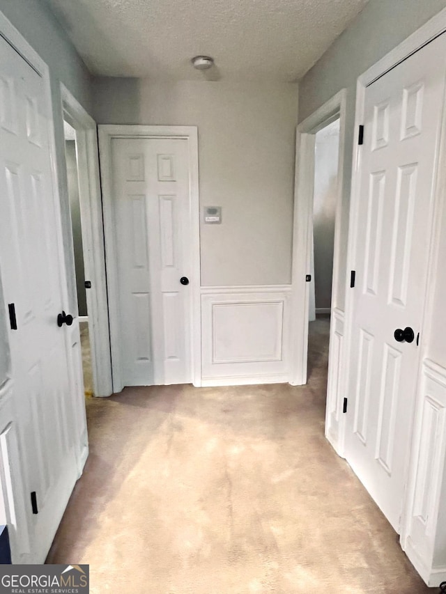 corridor featuring a textured ceiling and light carpet