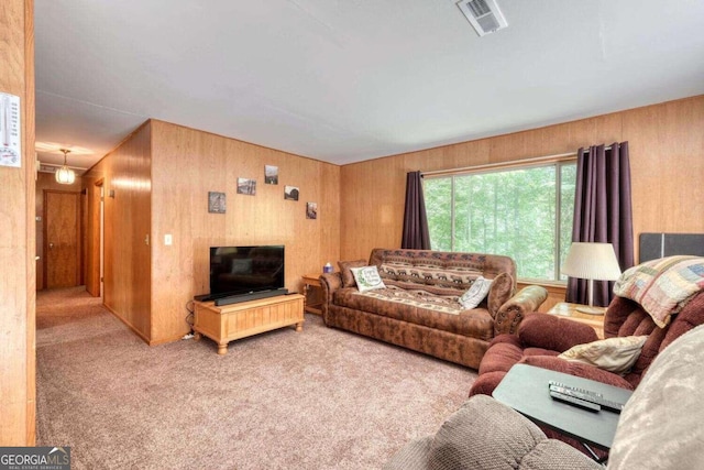 living area with wood walls, carpet flooring, and visible vents