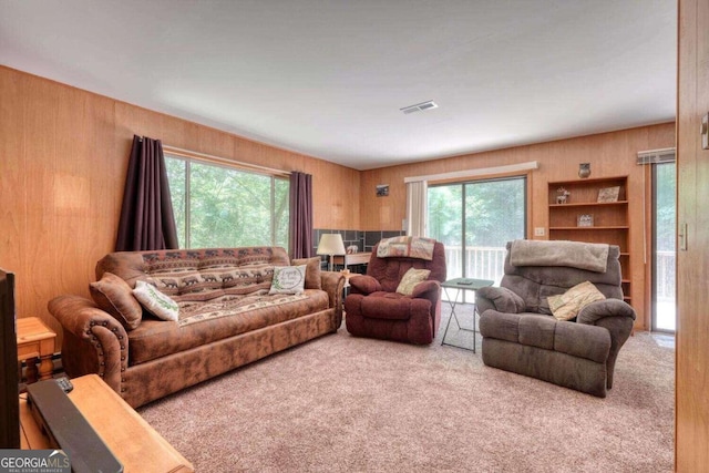 living room with carpet, wooden walls, and plenty of natural light