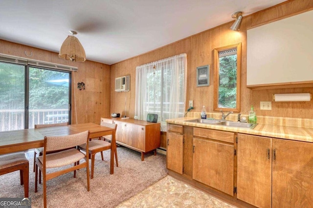 dining area featuring sink, wooden walls, light colored carpet, and a wall mounted air conditioner