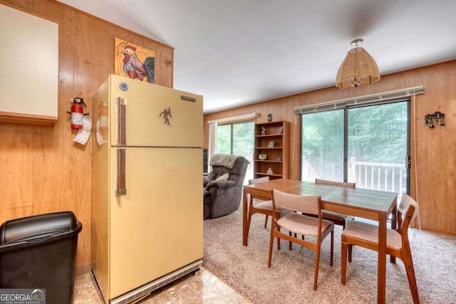 carpeted dining space featuring wooden walls