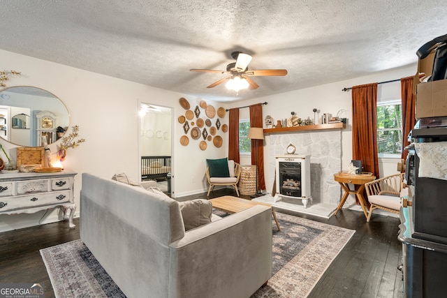 living room featuring a fireplace, ceiling fan, a healthy amount of sunlight, and dark hardwood / wood-style flooring