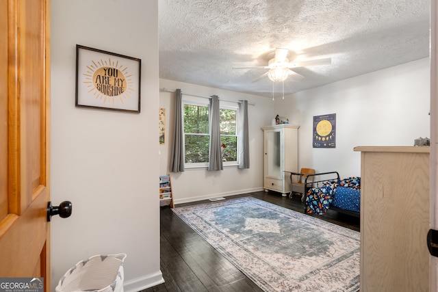 bedroom featuring ceiling fan, a textured ceiling, and dark wood-type flooring