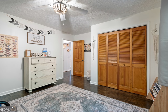 bedroom with ceiling fan, a closet, a textured ceiling, and dark wood-type flooring