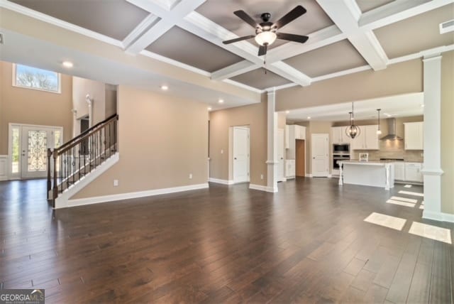 unfurnished living room with dark hardwood / wood-style floors, ceiling fan, and coffered ceiling