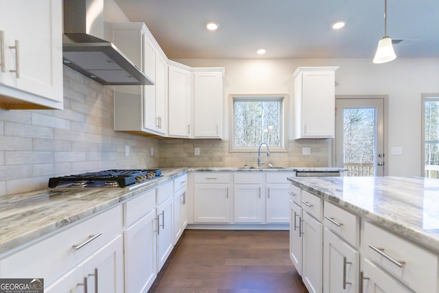 kitchen with white cabinetry, a wealth of natural light, and wall chimney range hood