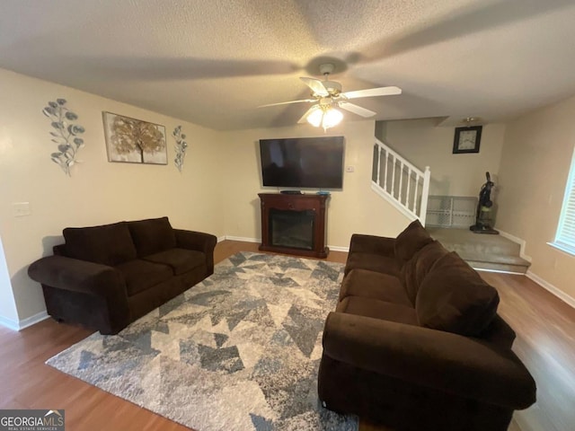 living room with ceiling fan, a textured ceiling, and wood-type flooring