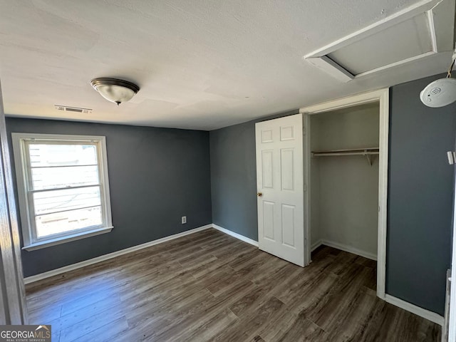 unfurnished bedroom with a closet, dark hardwood / wood-style floors, and a textured ceiling