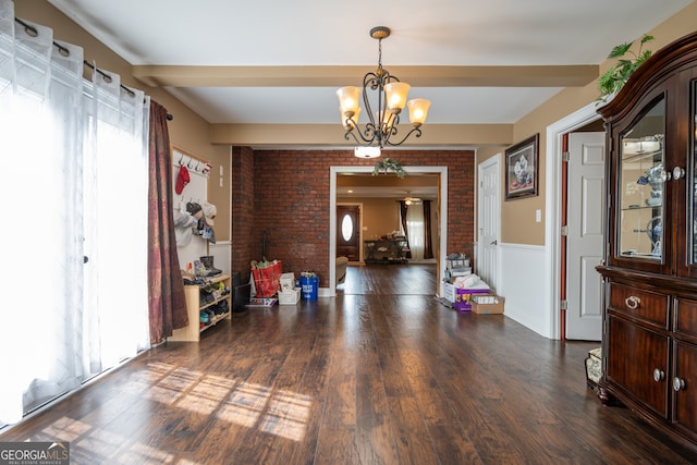 dining room with brick wall, an inviting chandelier, and dark hardwood / wood-style flooring