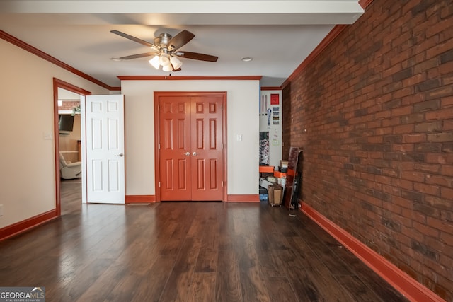 entryway featuring dark wood-type flooring, ceiling fan, crown molding, and brick wall